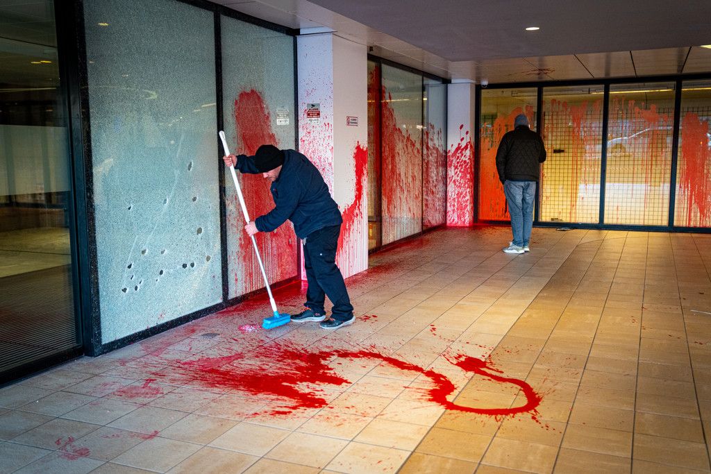 Schoonmakers bij deur beklad met rode verf